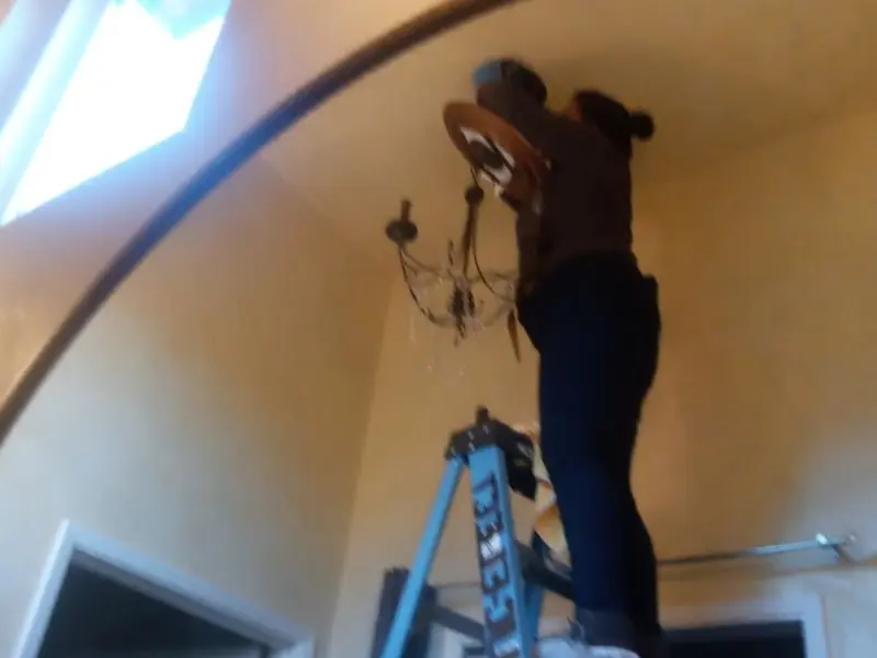 Electrician installing a chandelier in a Mount Penn residence